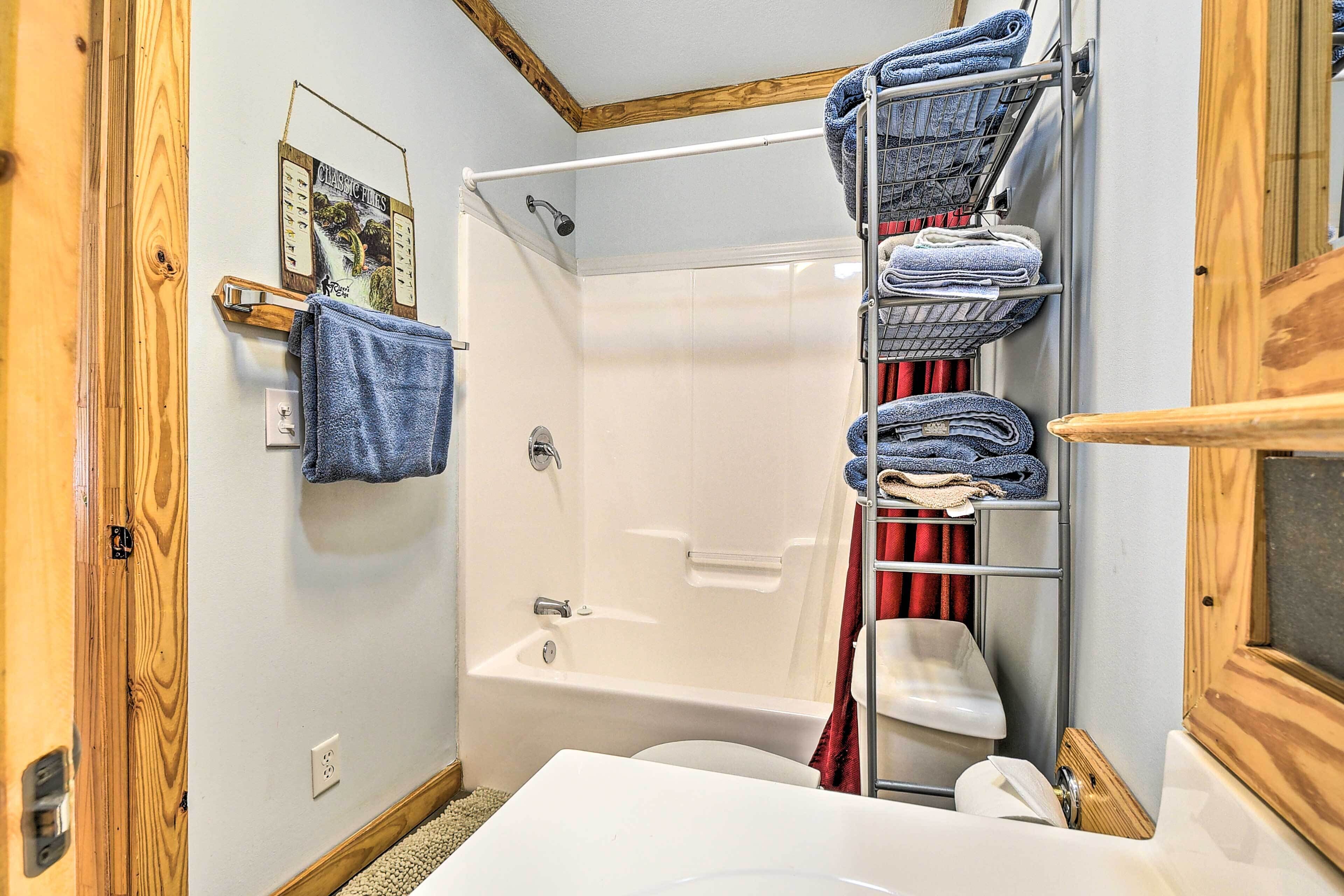 Une salle de bain avec une baignoire, des toilettes et une douche. On y trouve des serviettes et un porte-serviettes.