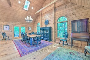 A spacious dining area with a wooden table and chairs, a chandelier, and a large cabinet.
