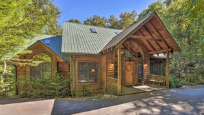 A log cabin with a porch, large windows, and a metal roof.