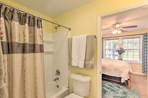 A bathroom with a shower, toilet, and a bed with a window.