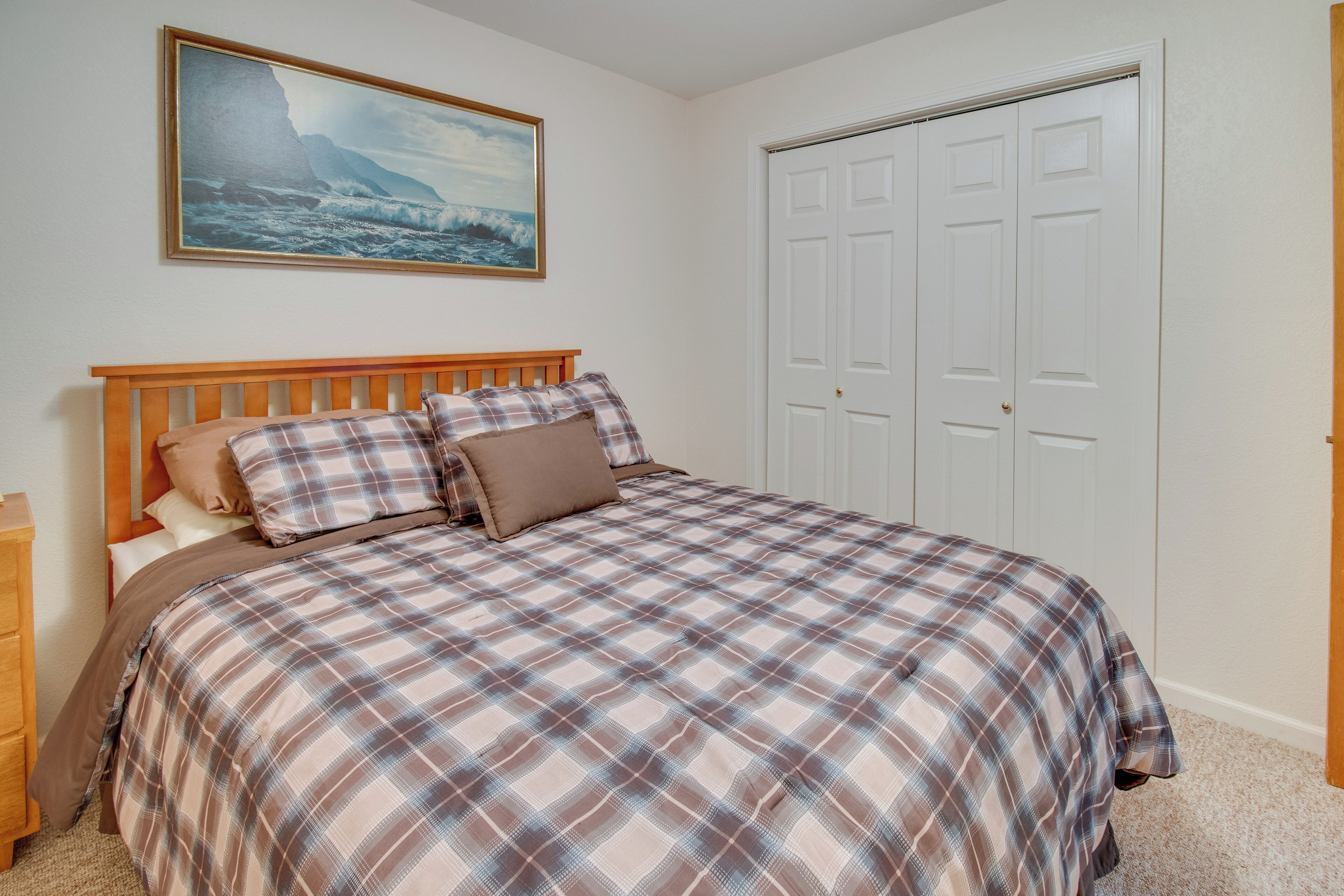 A bedroom with a wooden bed, a painting of a coastal scene, and a white door.