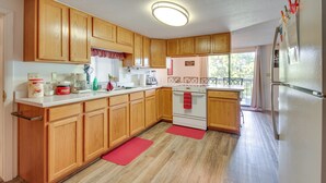 Una cocina con armarios de madera, encimera blanca, estufa y refrigerador.