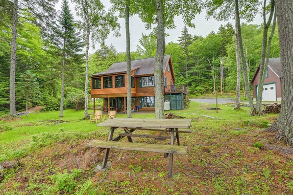 A cabin with a deck, surrounded by trees. - Lakefront Maine Retreat w/ Deck, Dock & Fire Pit! (Greenville)