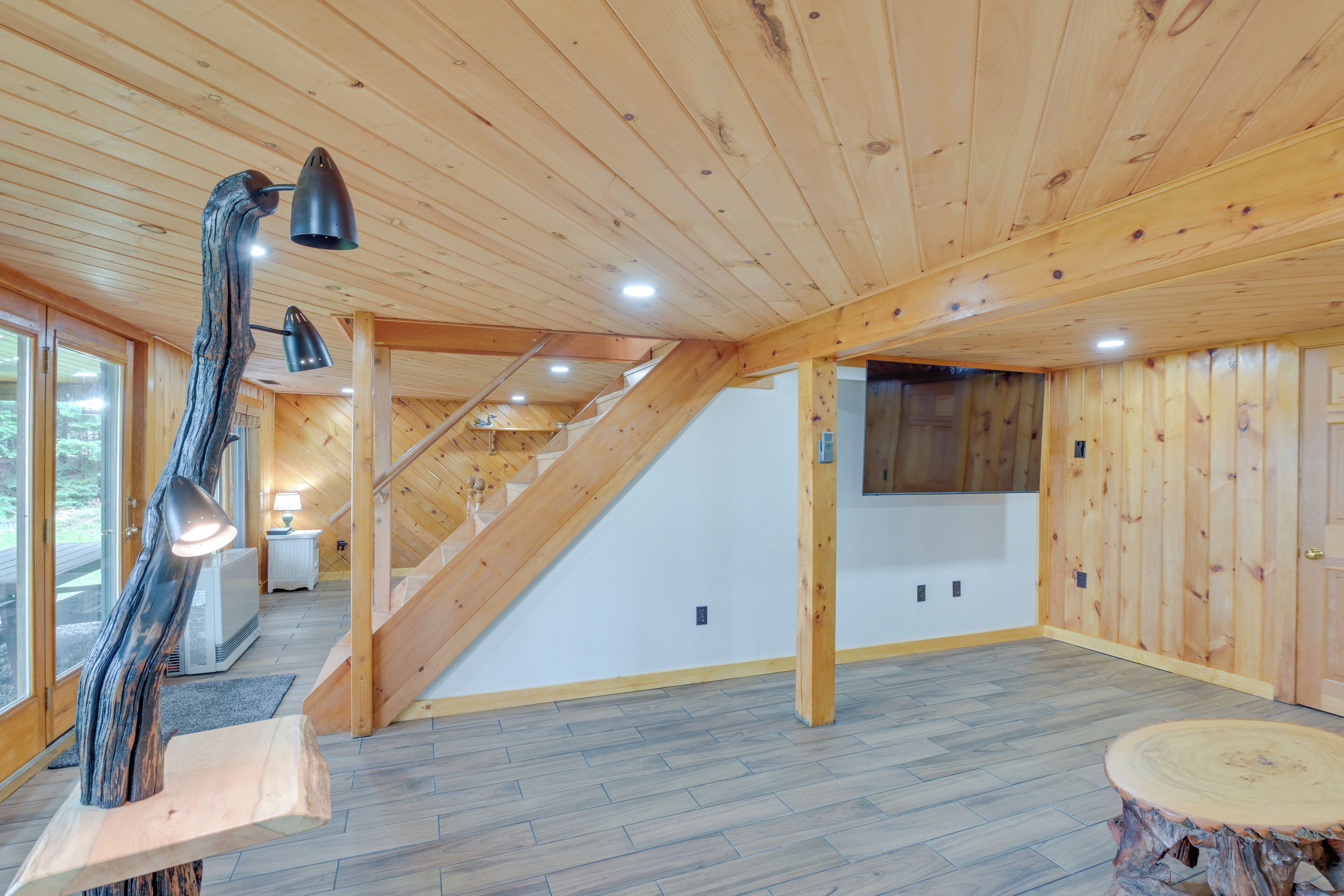Une pièce spacieuse dotée de planchers en bois, d’un escalier et d’un luminaire sculptural unique.