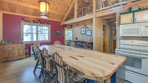A spacious kitchen with a large island, wooden chairs, and a white stove. - Lakefront Maine Retreat w/ Deck, Dock & Fire Pit! (Greenville)