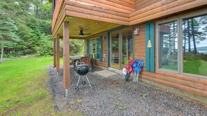 A wooden cabin with a covered patio, a grill, and outdoor seating. - Lakefront Maine Retreat w/ Deck, Dock & Fire Pit! (Greenville)