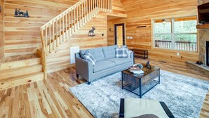 A wooden cabin interior with a staircase, a sofa, a coffee table, and a fireplace. - Family-friendly Murphy Cabin w/ Fire Pit! (Murphy)