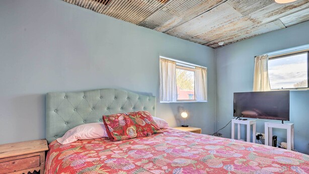 A bedroom with a bed, a television, and a window.