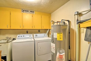 A laundry room with two washing machines, a water heater, and a sign indicating laundry services are available today or tomorrow.