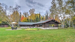 A log cabin with a stone foundation, a large porch, and a grassy yard.