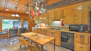 A wooden cabin-style kitchen with a central island, a dining area with chairs, and a dishwasher.