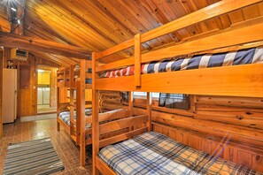 A cabin with bunk beds, wooden walls, and a kitchen area.