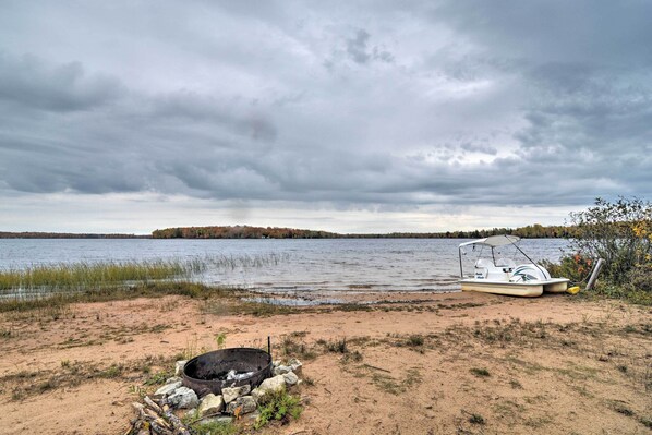 A lakeside scene with a boat and a fire pit.