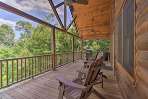 A wooden deck with Adirondack chairs and a grill, overlooking a forested area. - Hiwassee Hideaway' Cabin w/ Mountain Views! (Murphy)
