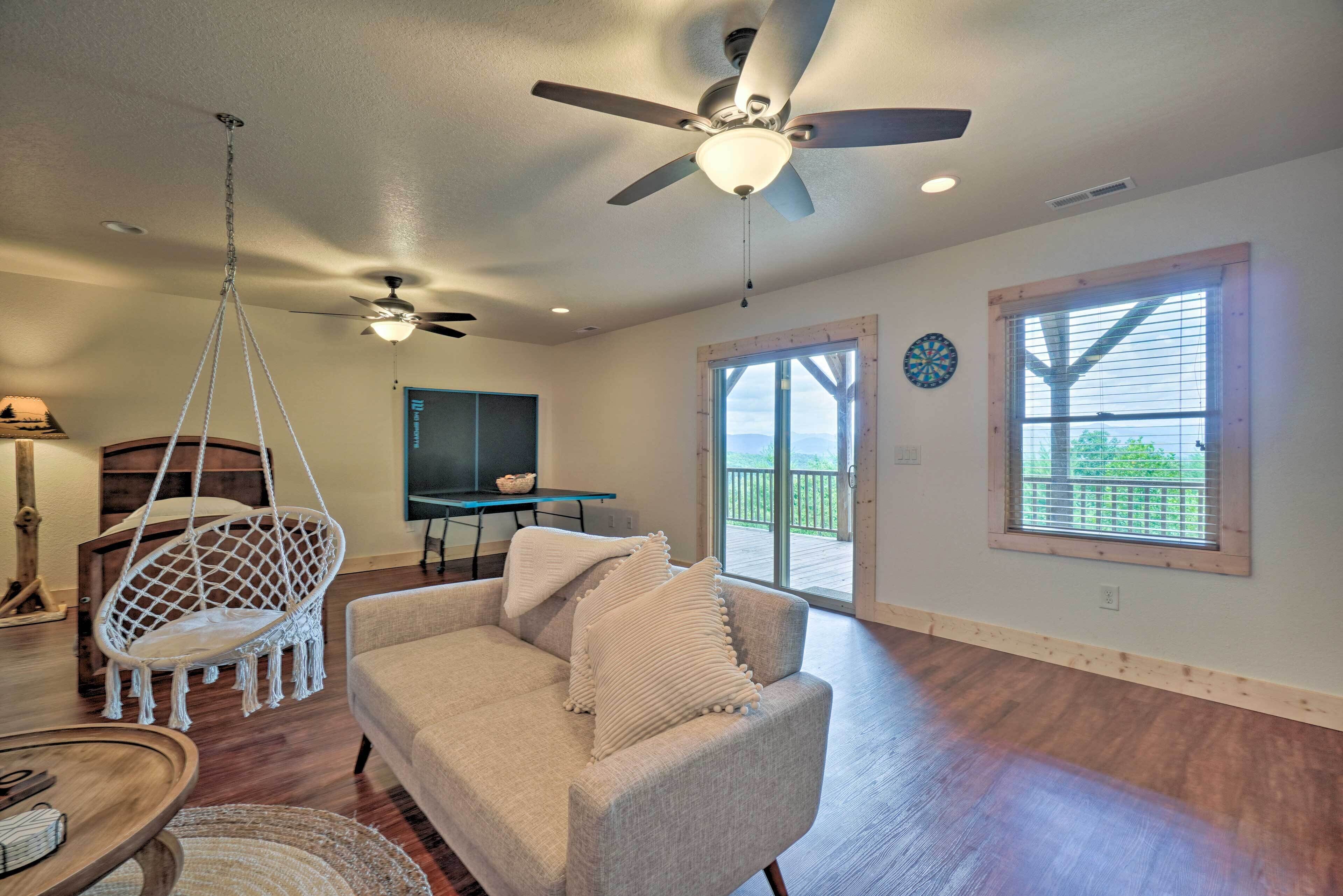 A spacious living room with a ceiling fan, a hanging chair, a sofa, and a dining table.