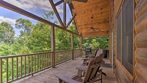 A wooden deck with Adirondack chairs and a grill, overlooking a forested area. - Hiwassee Hideaway' Cabin w/ Mountain Views! (Murphy)