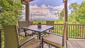 A covered outdoor seating area with wicker chairs and a table, overlooking a mountainous landscape. - Hiwassee Hideaway' Cabin w/ Mountain Views! (Murphy)
