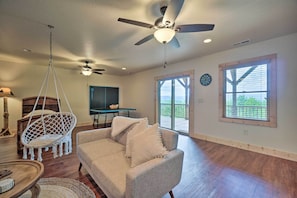 A spacious living room with a ceiling fan, a hanging chair, a sofa, and a dining table. - Hiwassee Hideaway' Cabin w/ Mountain Views! (Murphy)