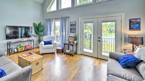 A spacious living room with a large TV, comfortable seating, a chessboard, and a balcony with a view. - Waterfront Piney Flats Home w/ Private Dock! (Piney Flats)
