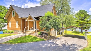 A two-story wooden house with a sloped roof, a covered porch, and a small front yard with a tree and a paved driveway. - Waterfront Piney Flats Home w/ Private Dock! (Piney Flats)