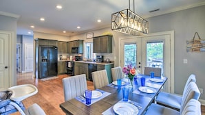 A modern kitchen with dark cabinets, a central island, and a dining area with a wooden table set for six. - Waterfront Piney Flats Home w/ Private Dock! (Piney Flats)