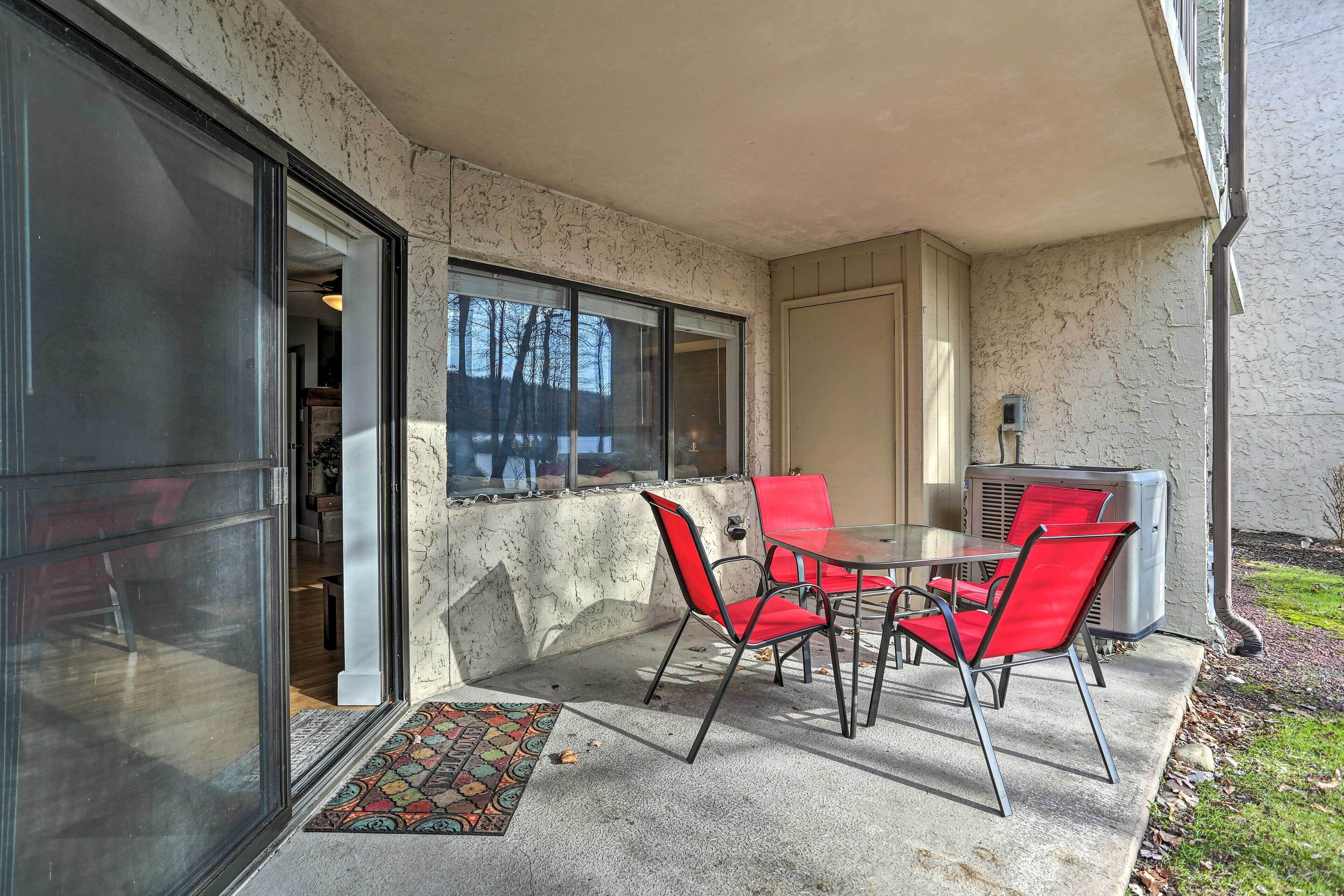 A patio with a table and chairs, a glass door, and a small air conditioning unit.