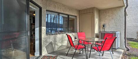 A patio with a table and chairs, a glass door, and a small air conditioning unit.