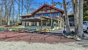 Un chalet à l’extérieur rouge et blanc, doté d’un patio couvert et d’un parking avec des tables de pique-nique.