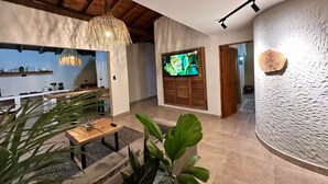 A modern living room with a TV, a dining area, and a kitchen in the background. - Increible Casa con Jacuzzi en Poblado-lleras (Medellín)