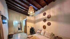 A bedroom with a bed, a hanging light fixture, a mirror, and a wall with decorative plates. - Increible Casa con Jacuzzi en Poblado-lleras (Medellín)