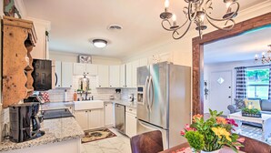 A modern kitchen with white cabinets, stainless steel appliances, and a dining area with a table and chairs. - Charming Country Cottage: 5 Mi to Downtown Tulsa! (Tulsa)