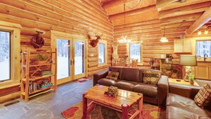 L’intérieur d’une cabane en rondins, avec une cheminée, des étagères en bois, un canapé en cuir et un coin repas.