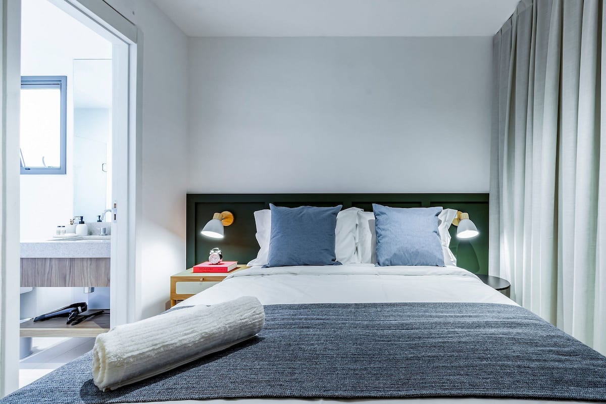 Une chambre d’hôtel moderne équipée d’un lit, de lampes de chevet, d’une table de nuit et offrant une vue sur la salle de bain.