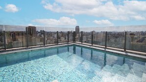 Una piscina sul tetto con vista sulla città, circondata da una barriera in vetro.