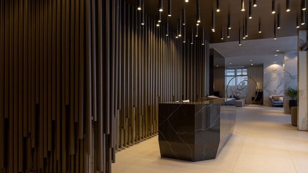 Un interno moderno con una reception, listelli di legno verticali e lampade a sospensione.