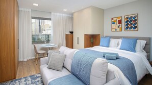 Una moderna camera d'hotel con un grande letto, un divano, un tavolo da pranzo e vista sulla città.