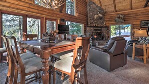 A log cabin interior with a dining area, fireplace, and seating. - Cascade Cabin w/ Mountain View & River Access (Cascade)