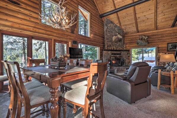 A log cabin interior with a dining area, fireplace, and seating. - Cascade Cabin w/ Mountain View & River Access (Cascade)