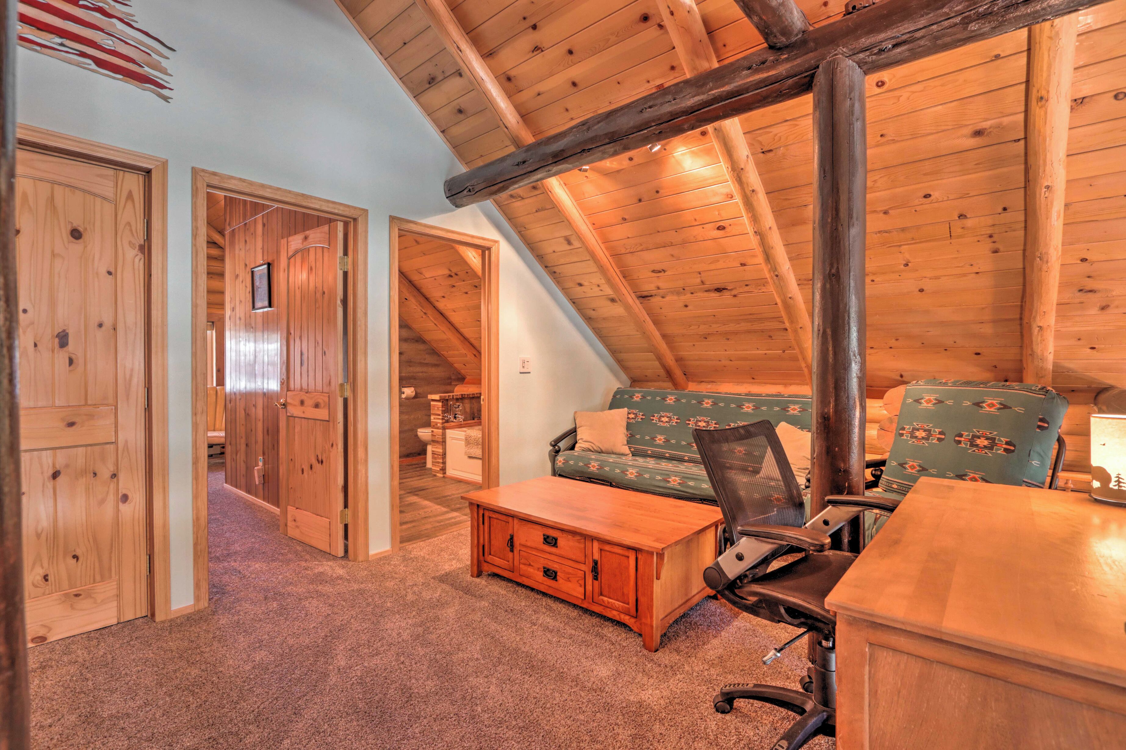 A cozy attic bedroom with wooden beams, a sofa, a desk, and a chair.