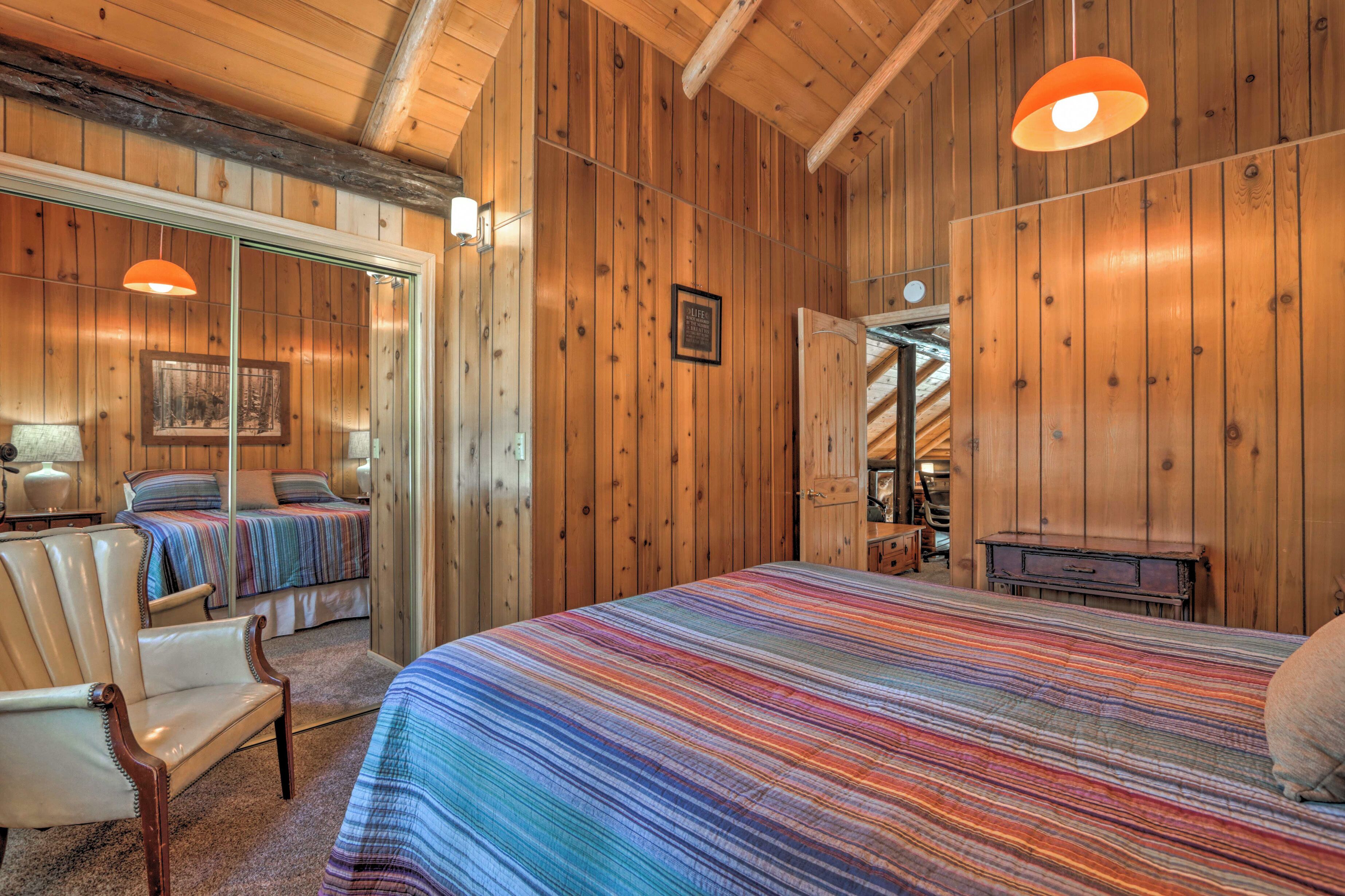 Um quarto com painéis de madeira, uma cama grande, uma cadeira e um banco.