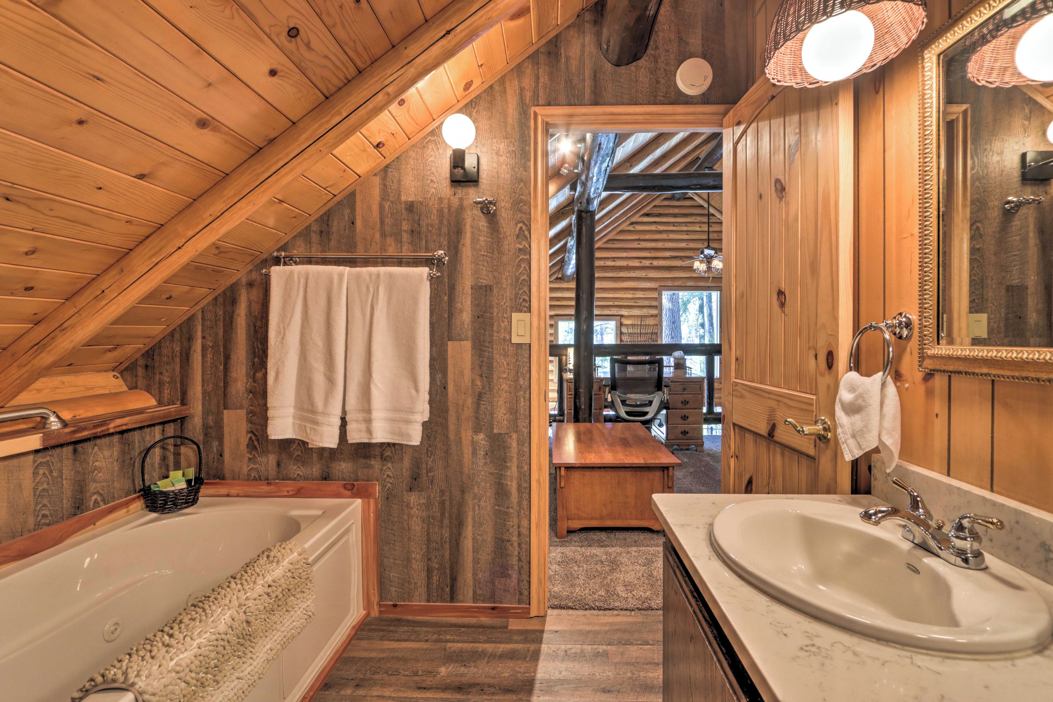 A wooden interior with a bathtub, sink, and towels.