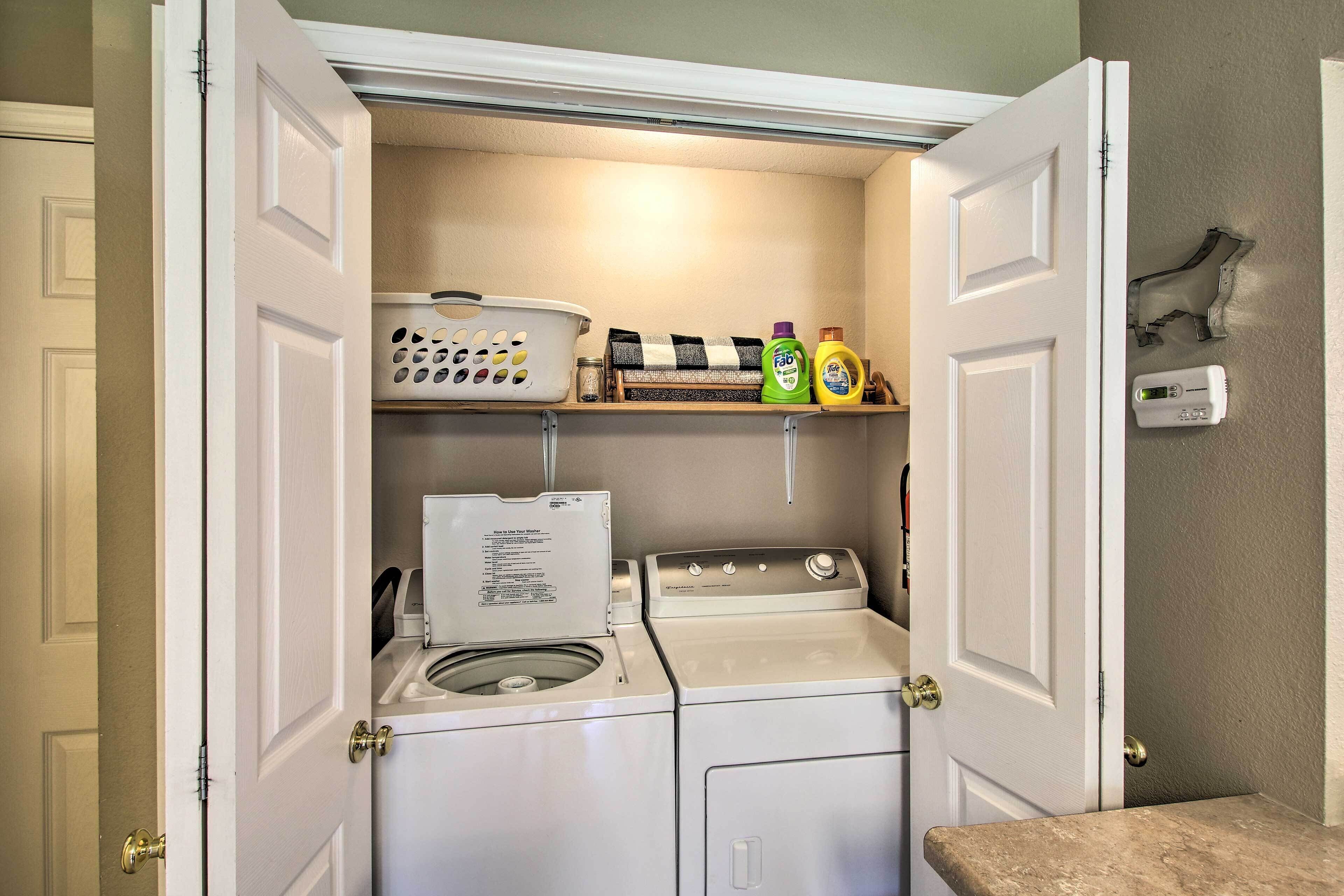 A laundry room with a washing machine, dryer, and shelves with laundry supplies.