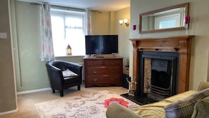 Een woonkamer met een open haard, een televisie, een bank en een fauteuil.