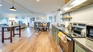 A spacious kitchen with wooden flooring, a dining area, and a living room. - Lakefront Mount Vernon Home w/ Private Dock! (Sedro-Woolley)