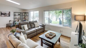 A spacious living room with a leather sofa, a coffee table, and a bookshelf. - Lakefront Mount Vernon Home w/ Private Dock! (Sedro-Woolley)