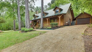 A log cabin with a porch, a garage, and a well-maintained lawn. - 'cape Royale' Luxury Livingston Cabin w/ Hot Tub! (Coldspring)