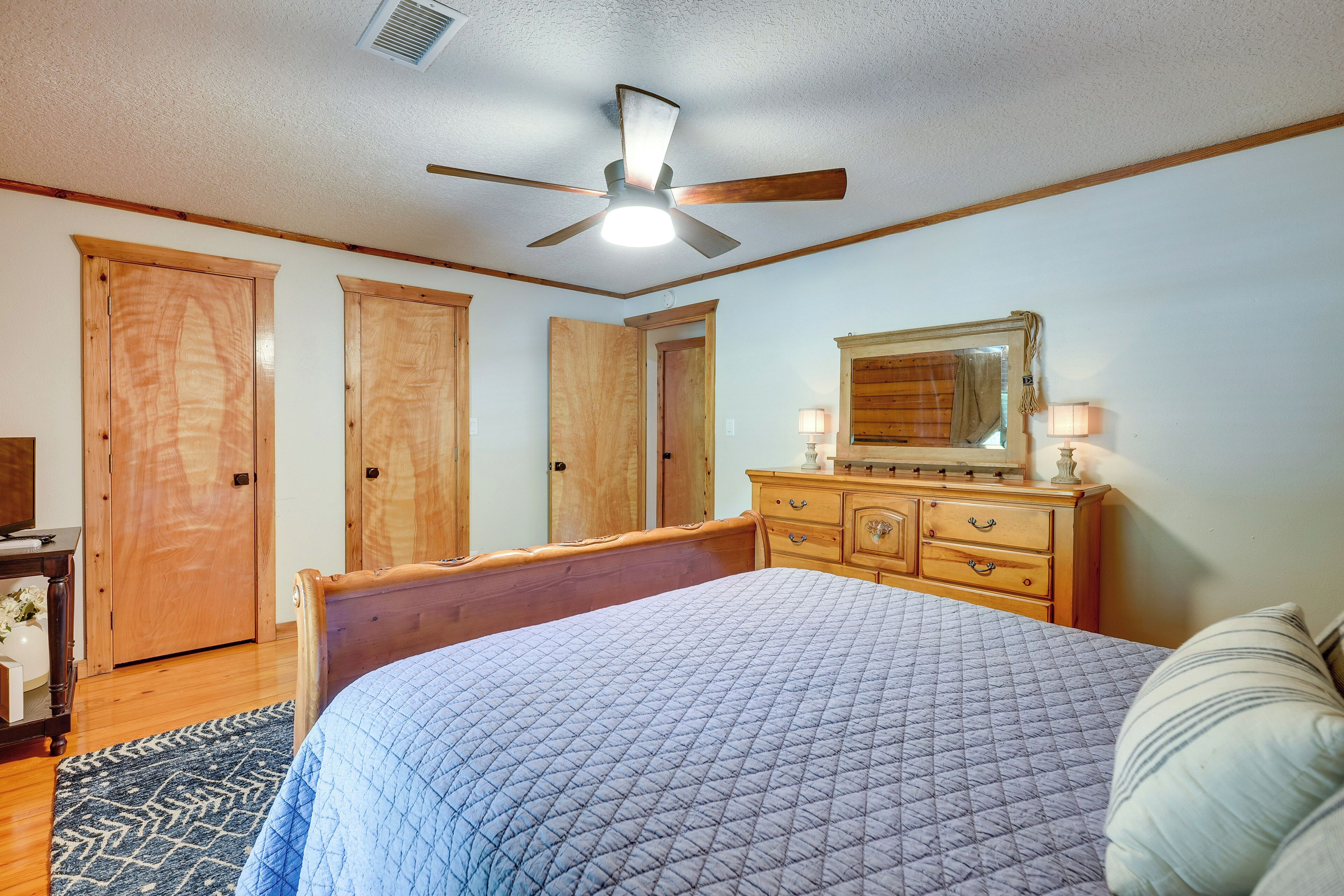 Un dormitorio con cama, armario de madera, cómoda y ventilador de techo.