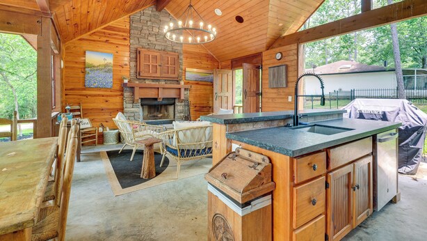 A spacious kitchen with wooden cabinets, a stone fireplace, and a large island with a sink. - 'cape Royale' Luxury Livingston Cabin w/ Hot Tub! (Coldspring)