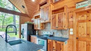 A kitchen with wooden cabinets, a stainless steel refrigerator, a double oven, and a granite countertop. - 'cape Royale' Luxury Livingston Cabin w/ Hot Tub! (Coldspring)