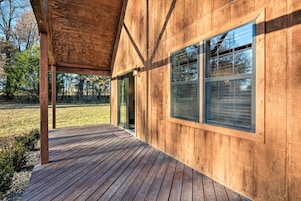 Un edificio de madera con terraza cubierta y ventanas grandes.